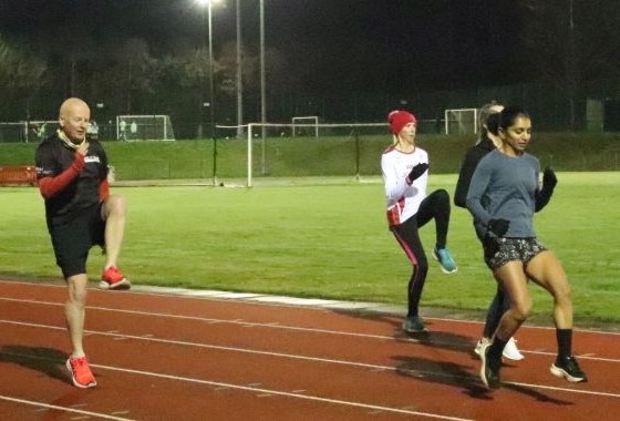 Runner performing high leg kicks or heel flicks during warm-up drills